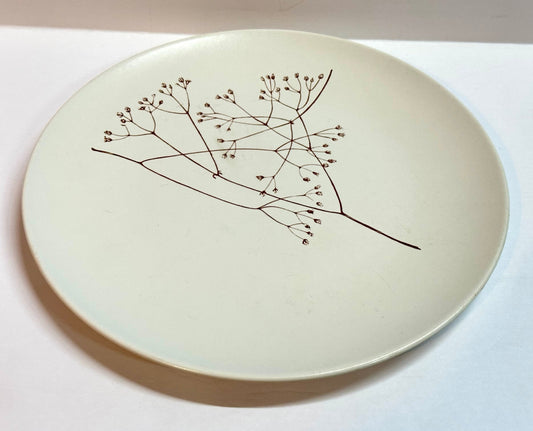 Ceramic plate with a black line drawing of a branch on a white background