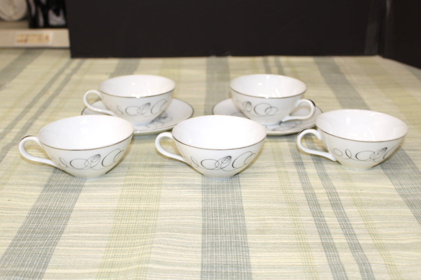 Side view of a vintage Meito China Tempo pattern flat cup showing the mid-century modern black atomic spiral design and reflective platinum rim.