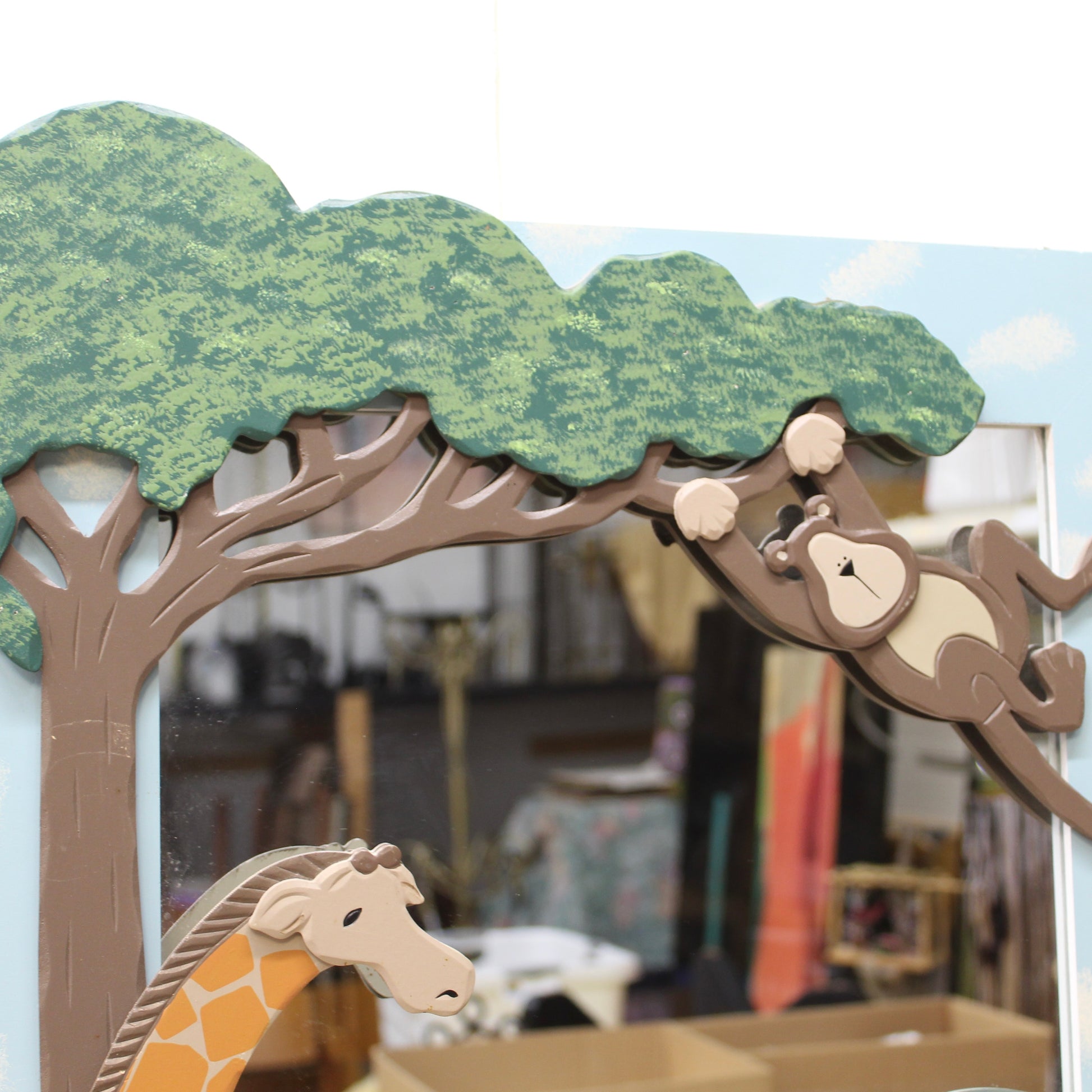 Decorative mirror with monkey and giraffe designs on a tree branch