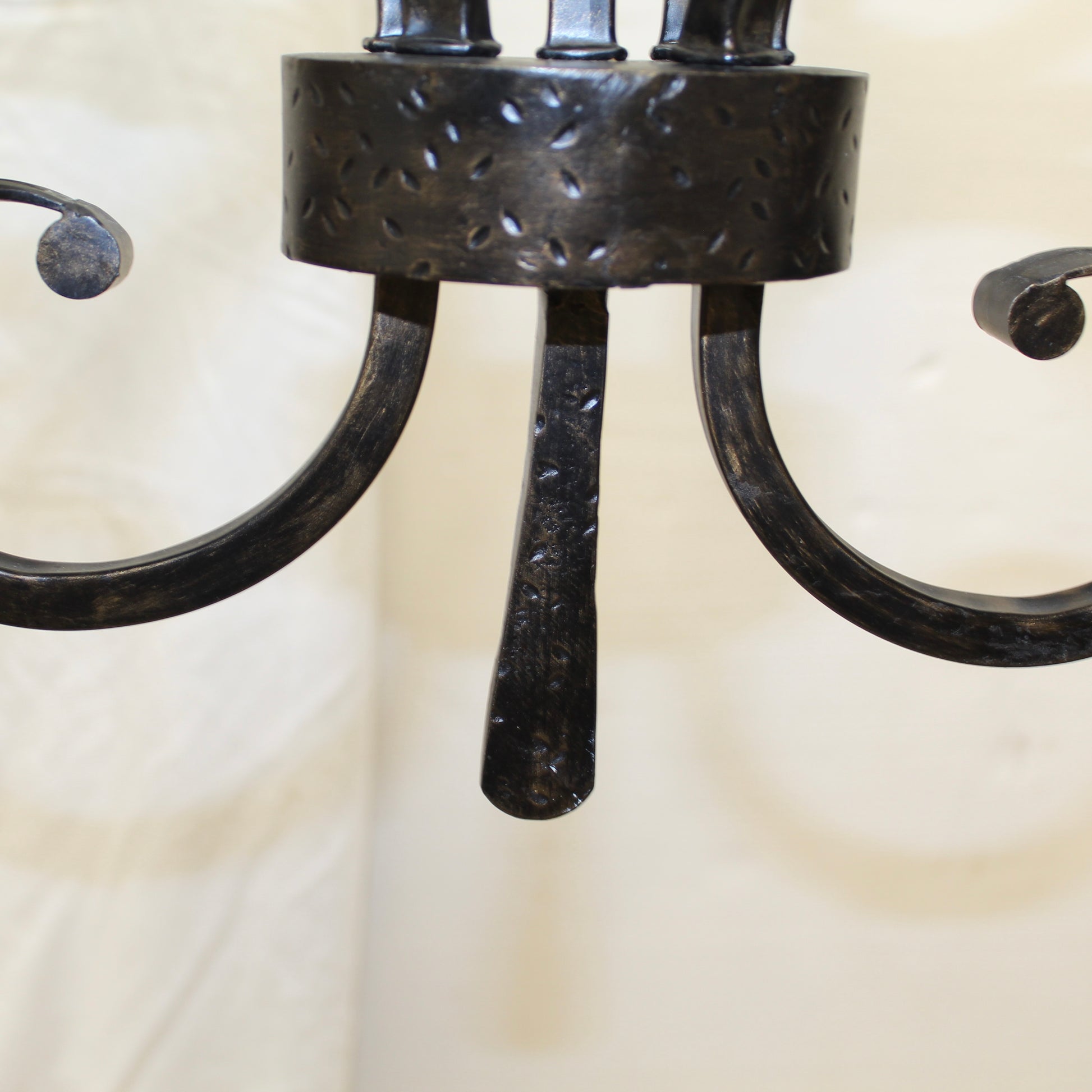 Close-up of a black metal chandelier with a textured design on a neutral background