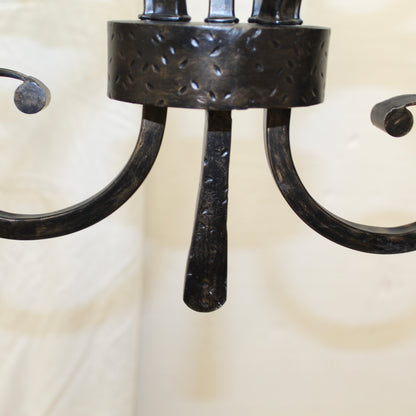 Close-up of a black metal chandelier with a textured design on a neutral background