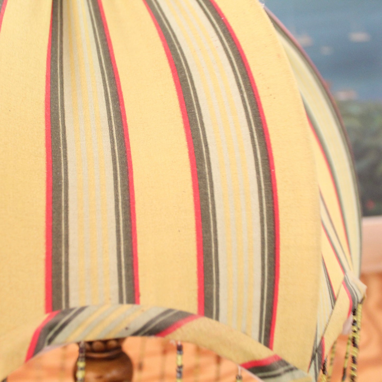 Dome-shaped fabric lamp shade with vertical stripes in beige, gray, yellow, and red.