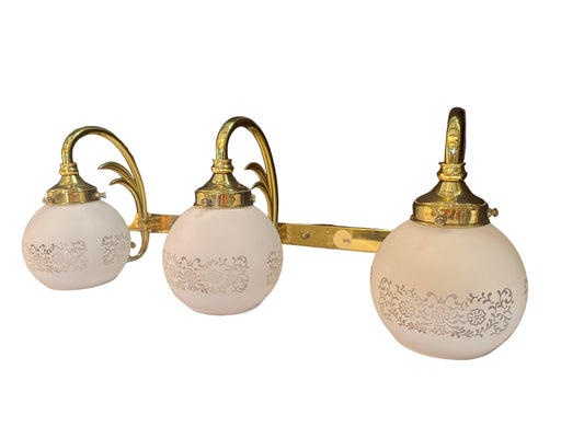 three light vanity light in brass with leafy detail and floral white frosted glass shades