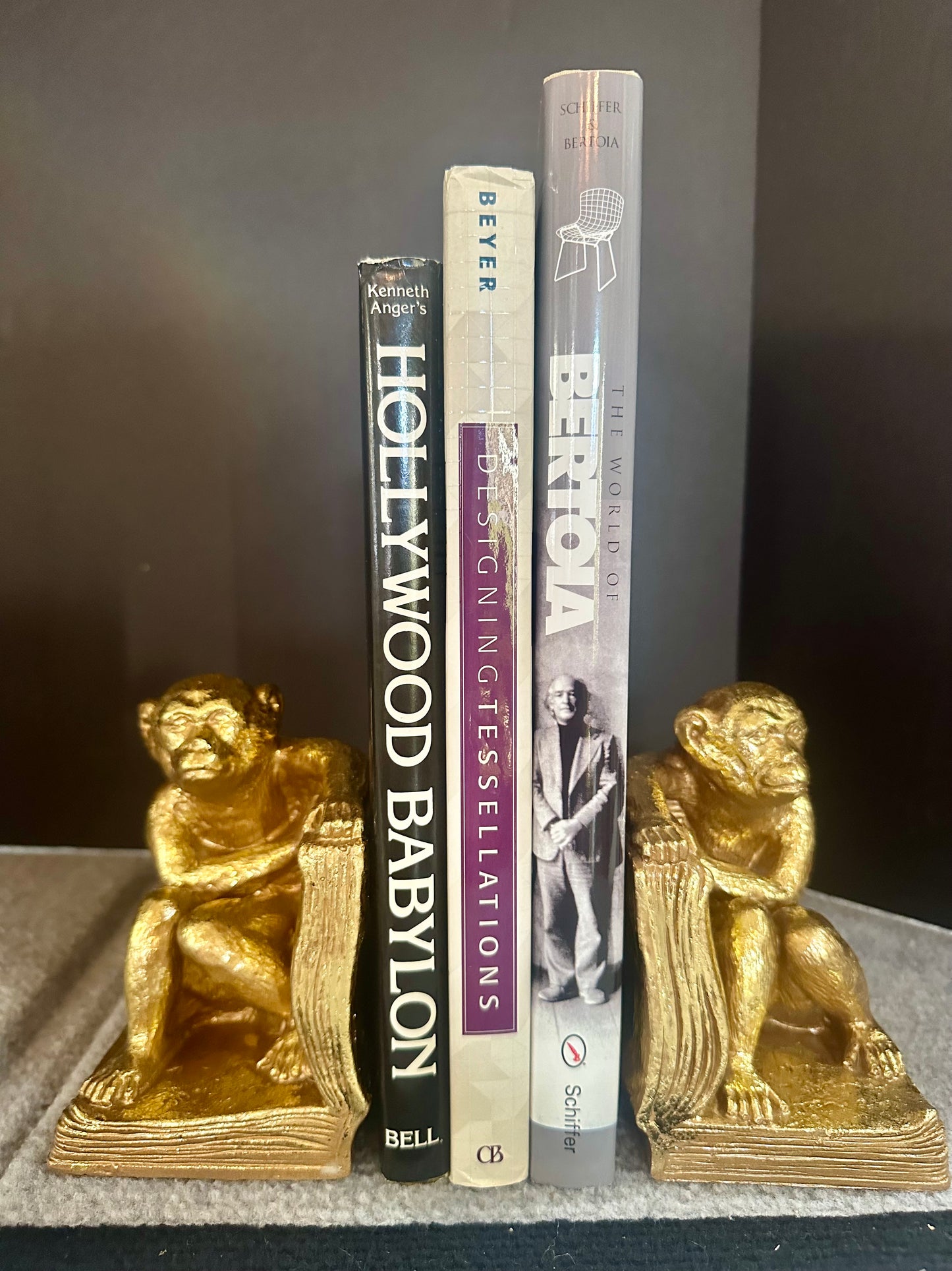 Three books with gold monkey bookends on a dark surface