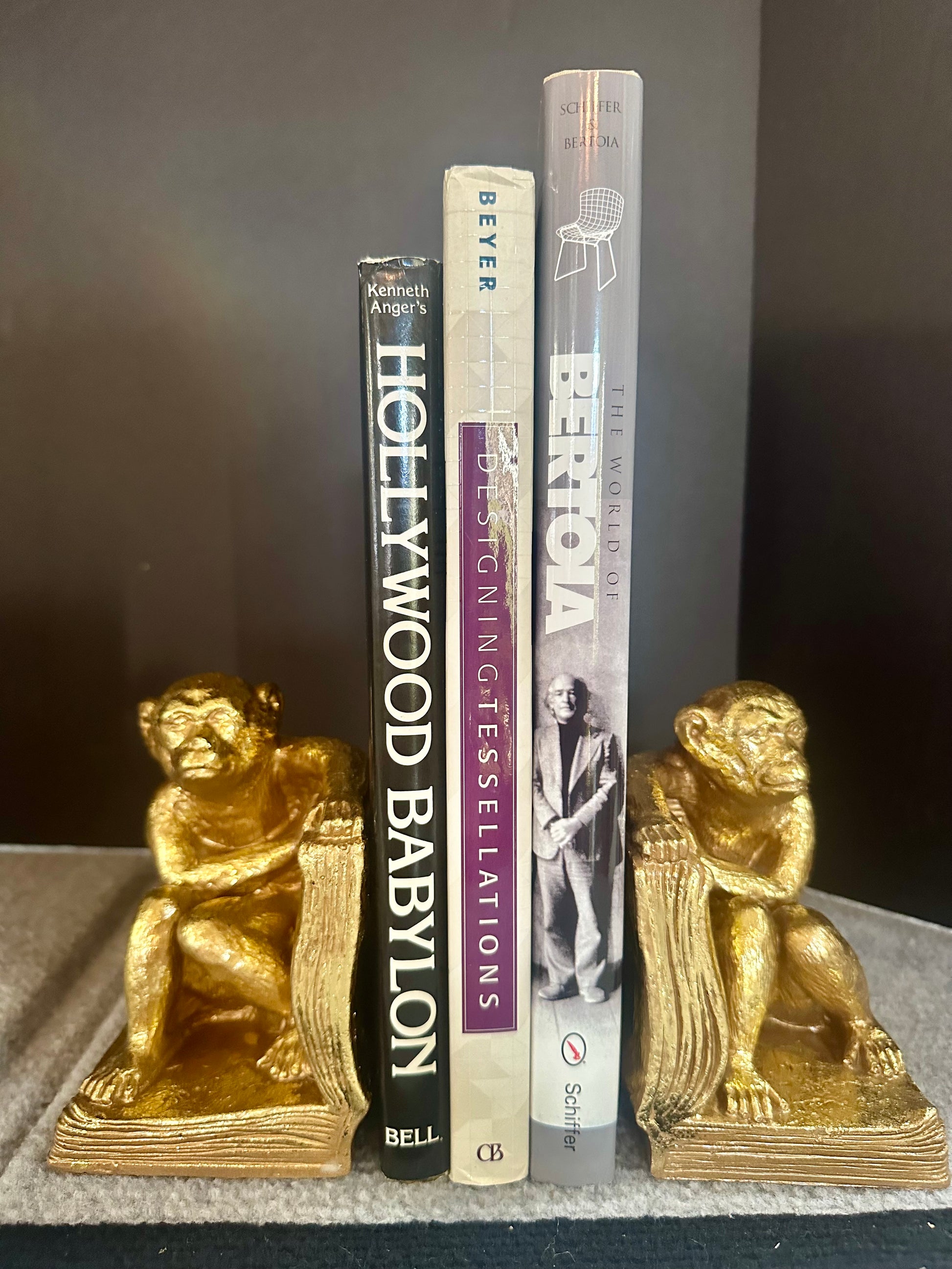Three books with gold monkey bookends on a dark surface
