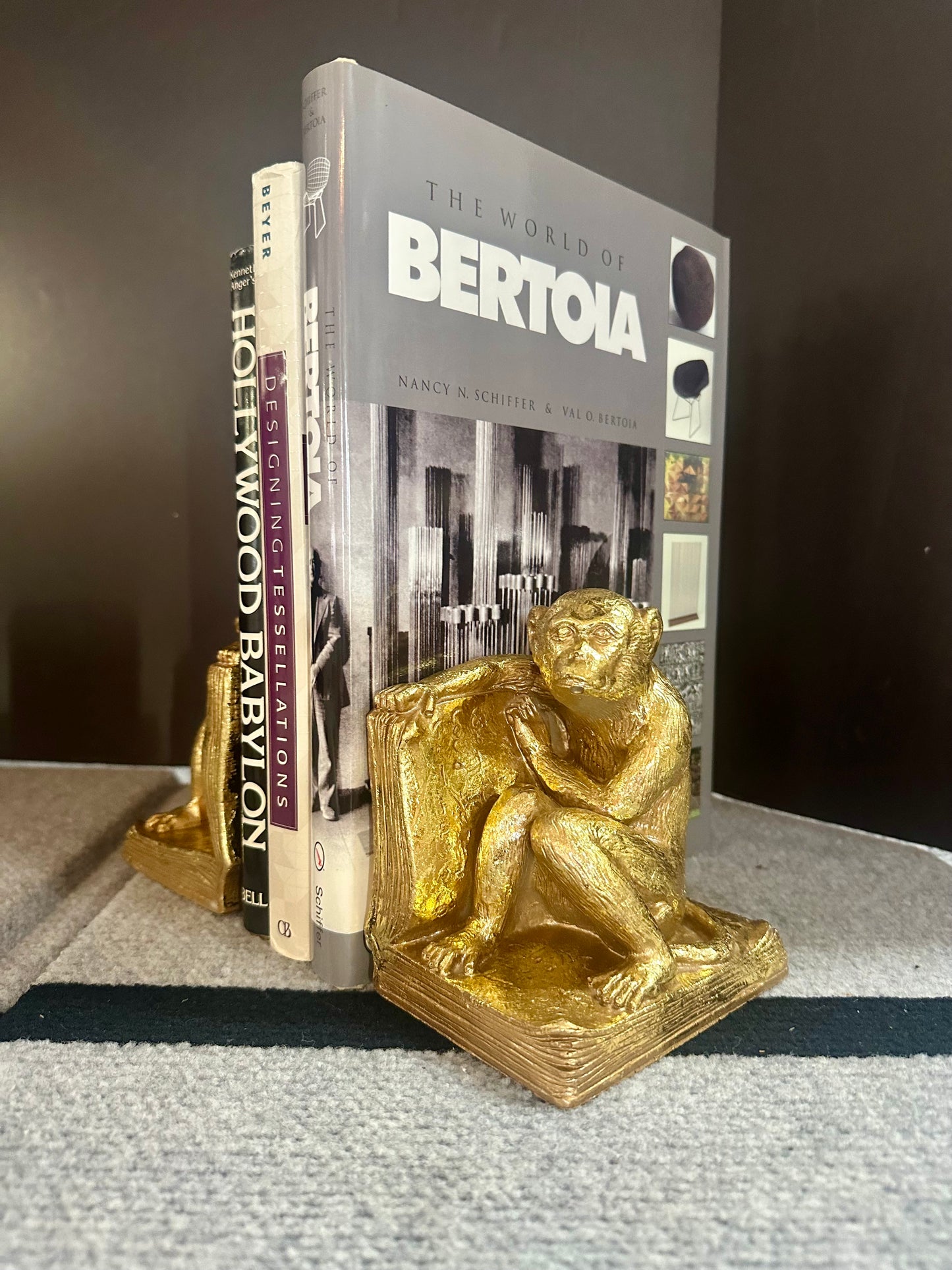 Gold monkey bookends holding books titled 'The World of Bertoia' and 'Hollywood Babylon'.