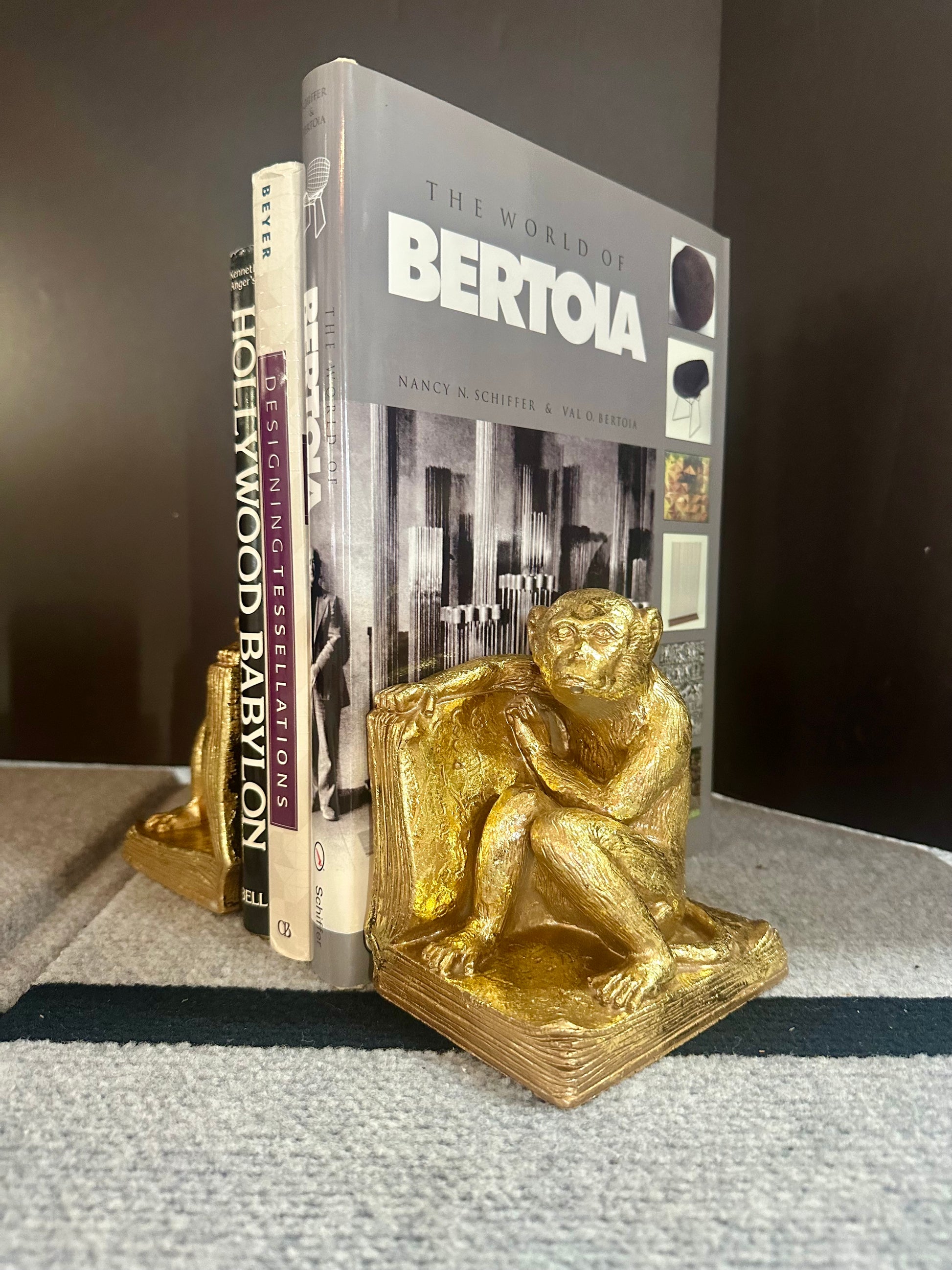 Gold monkey bookends holding books titled 'The World of Bertoia' and 'Hollywood Babylon'.