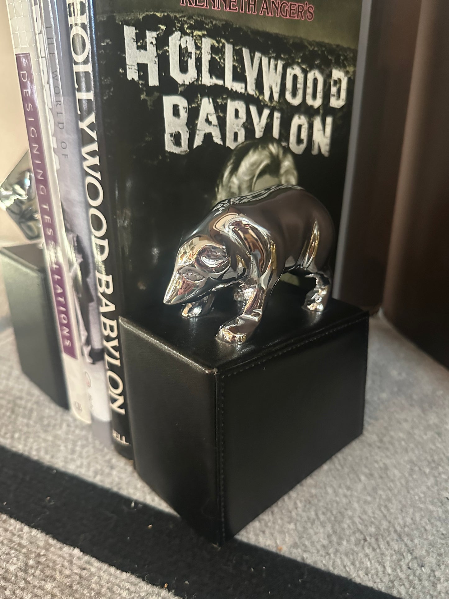 Stack of books titled 'Hollywood Babylon' with a decorative item on top.