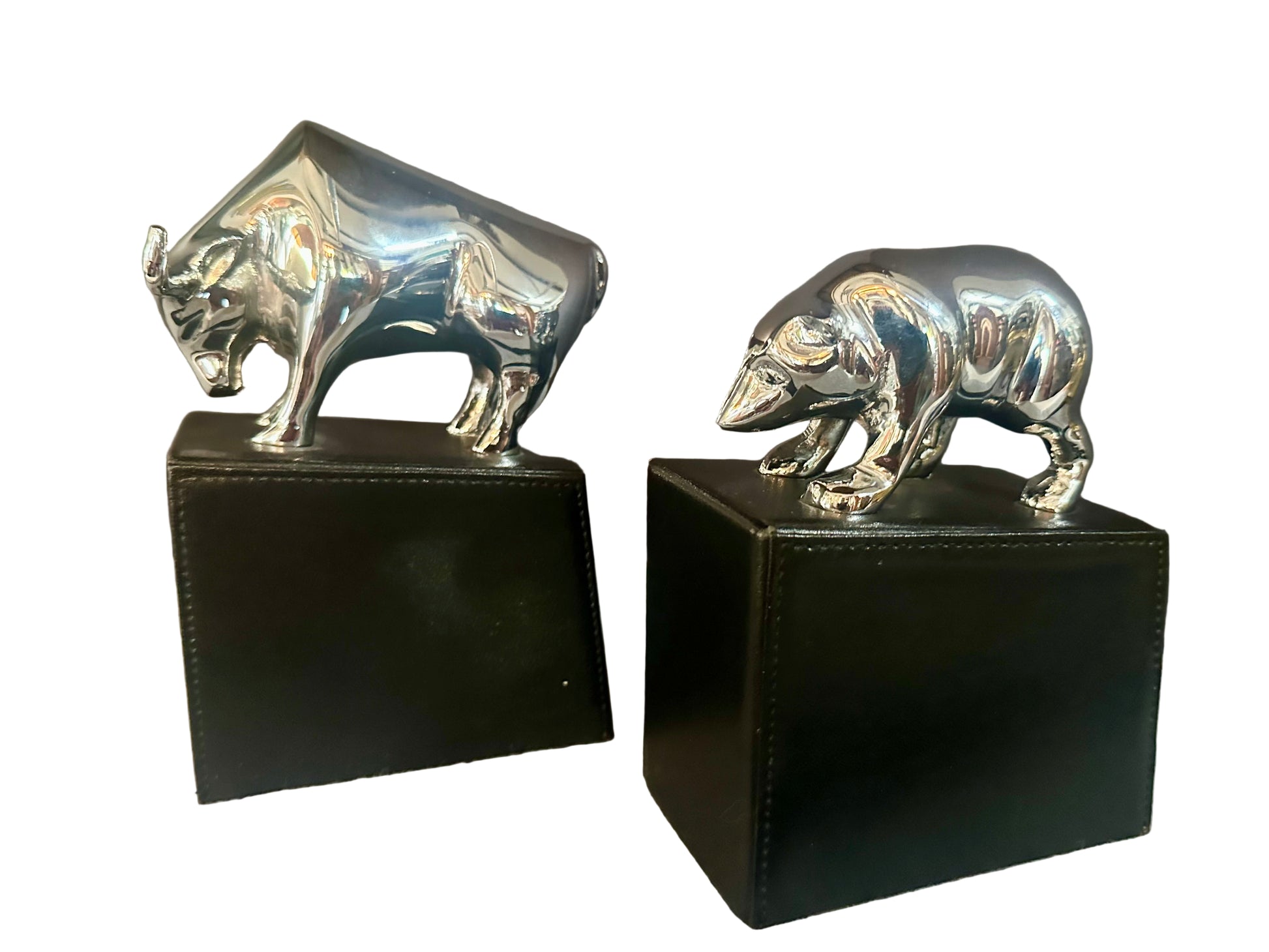 Silver bull and bear figurines on black stands against a neutral background