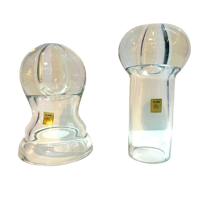 Two clear glass oil candles on a white surface with a light gray background