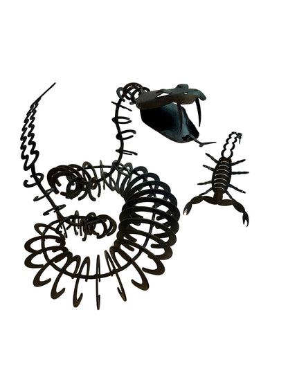 Black metal scorpion sculptures on a white surface with a blurred background