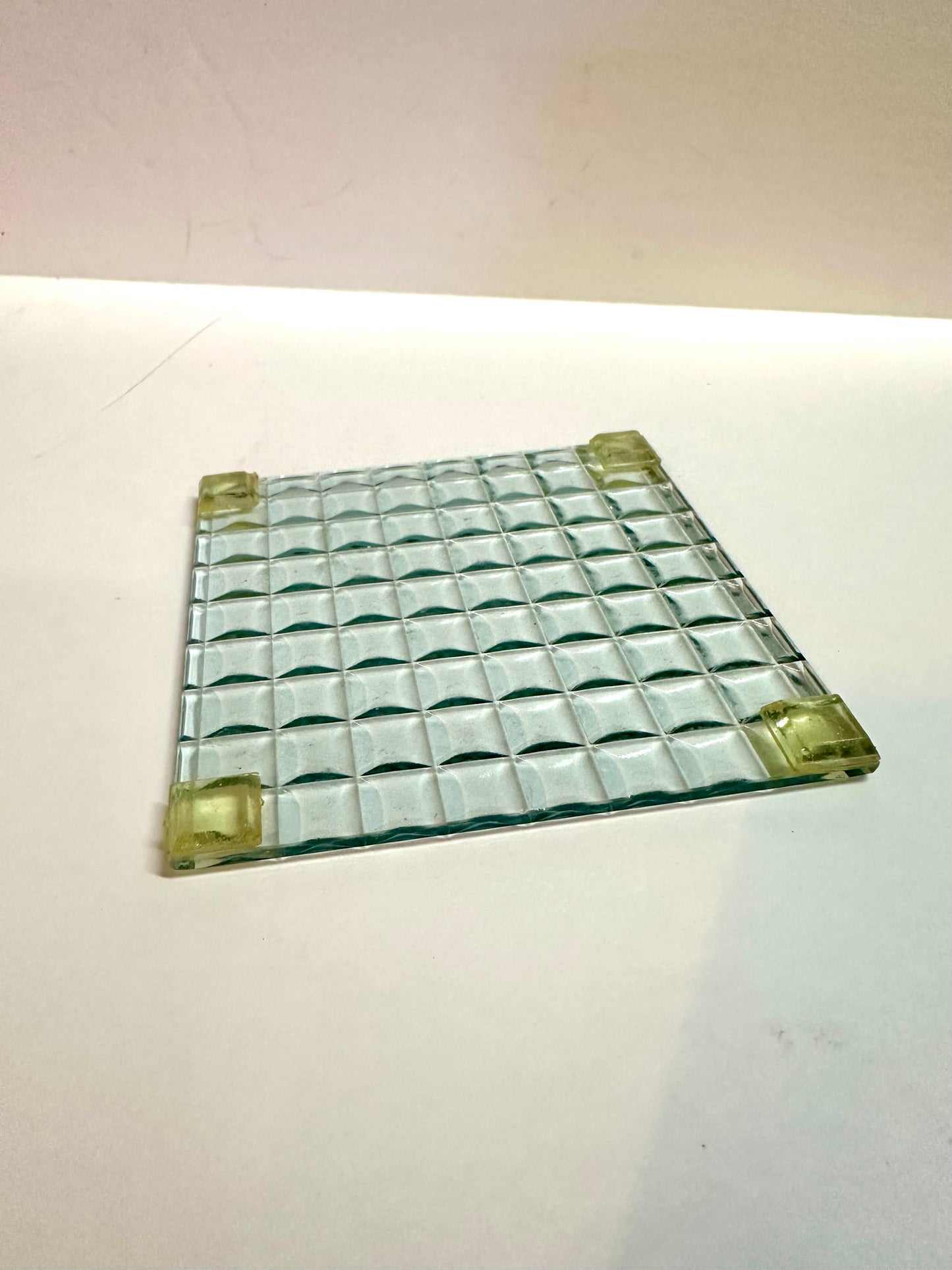 Square glass drink coaster with a grid pattern 
