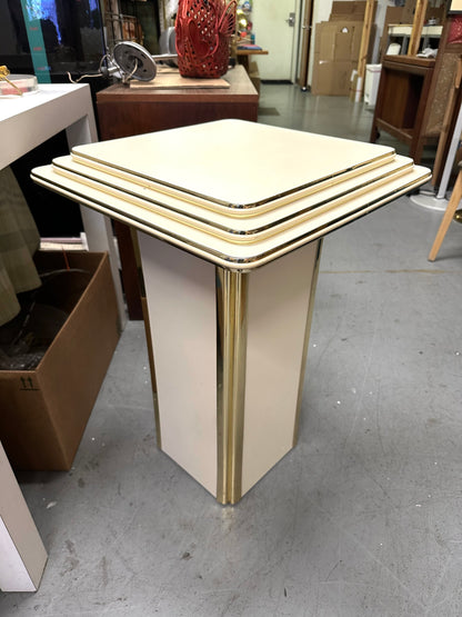 Off white stepped pedestal with brass edging. setting