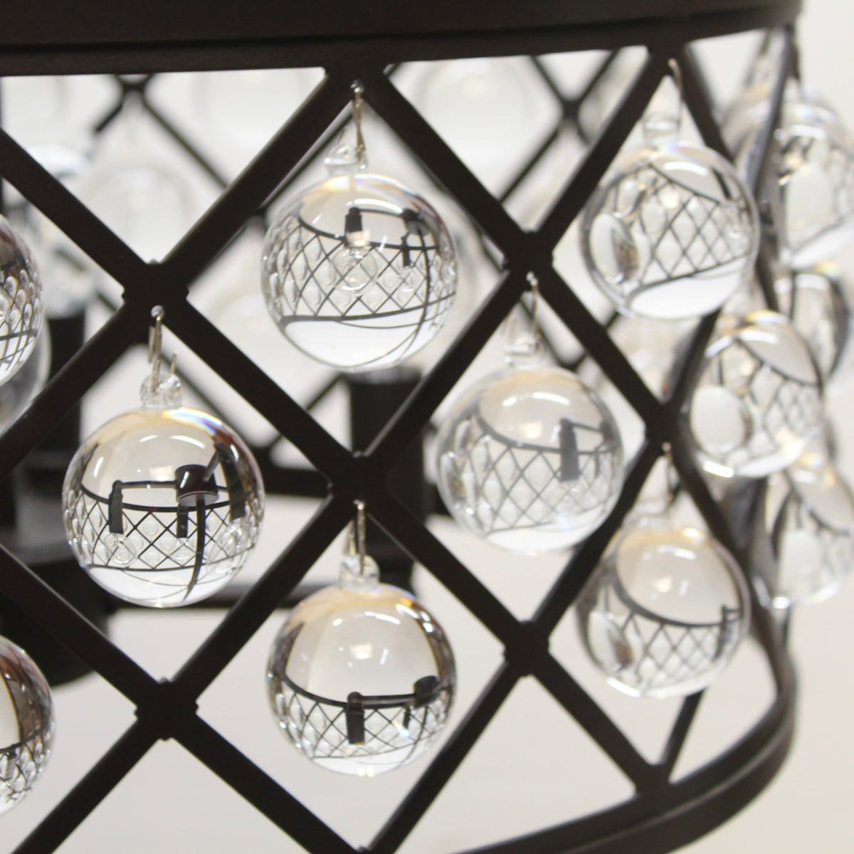 Decorative glass balls with black and white designs hanging on a black metal grid.