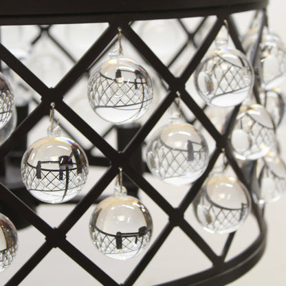 Decorative glass balls with black and white designs hanging on a black metal grid.