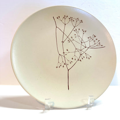 Ceramic plate with a black branch design on a white background