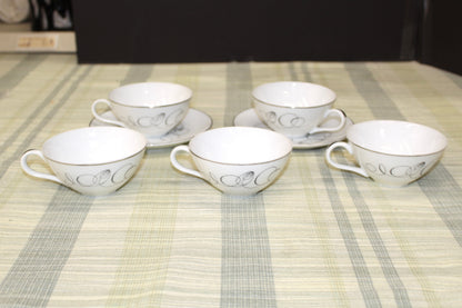 Side view of a vintage Meito China Tempo pattern flat cup showing the mid-century modern black atomic spiral design and reflective platinum rim.