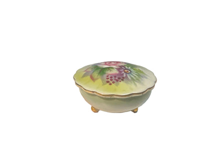 small round porcelain footed trinket box with painted pink flowers on the removable top. Gold edging on top and feet.